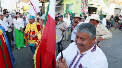 Mexican-People-In-Colorful-Costumes-Marching-In-The-Street-With-Flags-And-Musical-Instruments-During-Ancestral-Dances-Parade-In-Tuxpan,-Jalisco,-Mexico