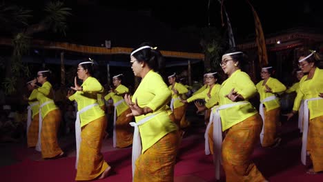 Asian-Women-Dancing-Traditional-Dance-at-Balinese-Temple-Bali-Hindu-Religion-Art-as-Offering-for-the-Gods,-Wearing-Ceremonial-Yellow-Costumes,-Glasses-and-Makeup