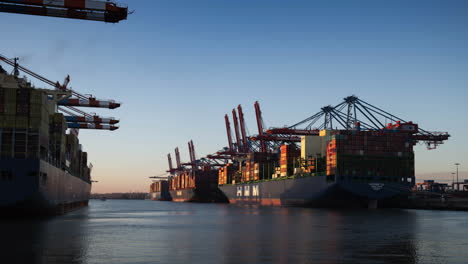 Große-Containerschiffe-Im-Hamburger-Hafen,-4k-Zeitraffer-Von-Tag-Zu-Nacht,-Langsames-Herauszoomen,-Sauberer-Himmel,-Wirtschaft,-Export,-Markt,-Symbol