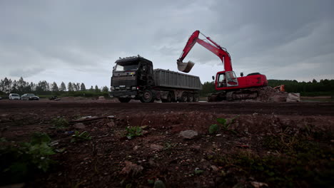 Digger-transporting-sand-and-stone-into-transporter-on-construction-site