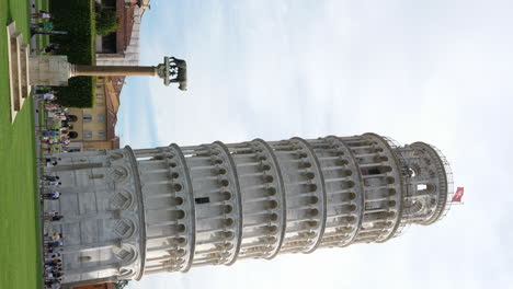 Vertical-static-shot-of-Leaning-Tower-of-Pisa-on-sunny-day,-tourists-nearby