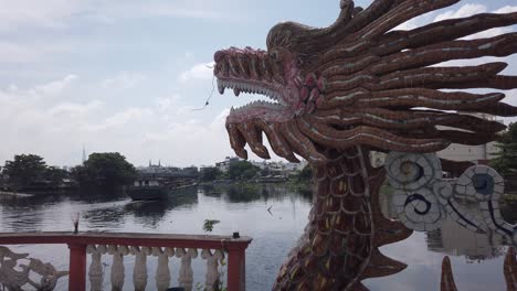 Dragon-sculpture-and-freighter-at-Phu-Chau-pagoda-or-floating-temple,-an-old-Chinese-style-Buddhist-place-of-worship-in-the-middle-of-the-Phuam-Thuat-river-in-Go-Vap,-Ho-Chi-Minh-City,-Vietnam