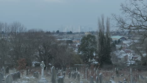 Canary-Wharf-on-Horizon,-Bleak-Snowy-Graveyard-in-Foreground-on-a-Winters-Day