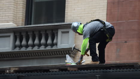 Construction-Worker-Standing-Using-Hammer-On-Long-Nails-On-Site-In-New-York