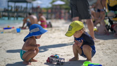 Zwei-Junge-Babys-Aus-Verschiedenen-Ethnien-Spielen-An-Einem-Heißen-Sommertag-Mit-Autospielzeug-Am-Strand