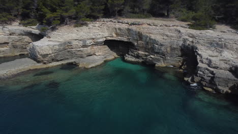 Drohnenaufnahme-Einer-Felsigen-Küste-In-Kroatien---Drohne-Fliegt-Von-Einer-Kleinen-Felsenhöhle-Weg