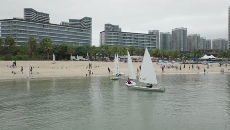 Sailing-dinghies-arrive-at-the-beach-shore-in-Huizhou,-China