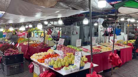 Customer-looking-at-the-fruits-,-vendor-busy-packing-fruits-at-stall-in-Chong-Pang-City,-Yishun,-Singapore