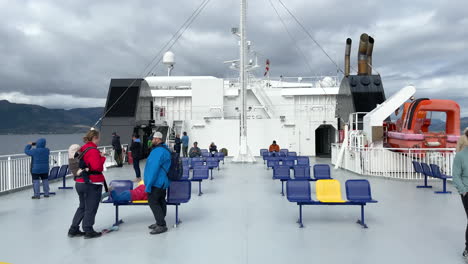 Static-shot-of-people-waiting-and-sightseeing-on-the-deck-of-a-ferry-as-it-makes-a-crossing-on-a-cloudy-but-sunny-day