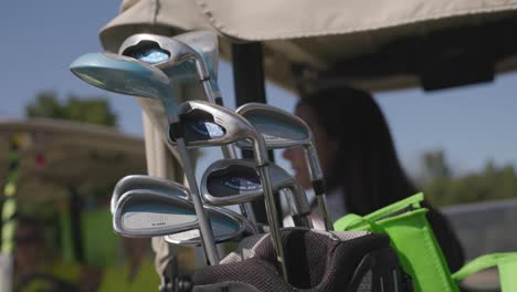 Slow-motion-smoothly-moving-shot-of-golf-clubs-with-people-in-the-background