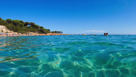 People-bathing-at-famous-Palombaggia-idyllic-beach-with-turquoise-sea-water-in-Corsica,-France