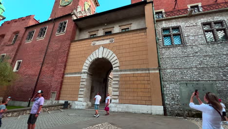 People-At-The-Vasa-Gate-In-Wawel,-Entrance-Gate-Leading-To-The-Wawel-Hill-Next-To-Clock-Tower-In-Krakow,-Poland