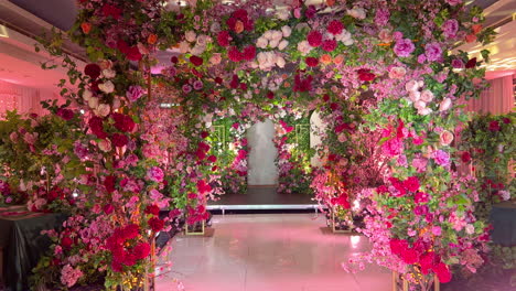 Beautiful,-romantic-arch-made-of-artificial-roses-illuminated-by-stage-lighting