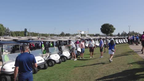 long-line-of-golf-carts-and-people-crowing-around-them-slow-motion