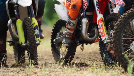 Group-of-Motocross-Racers-Get-Ready-for-Competition-Race-Sitting-on-Motorcycles-Waiting-for-Start---low-angle-panning