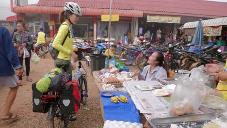 Sporty-asian-woman-buying-food-in-street-stall-of-market-in-Laos,-Southeast-Asia
