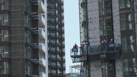 Engineers-and-Construction-Workers,-in-Hoist-Traveling-Down-a-Tower-Block-on-Building-Site