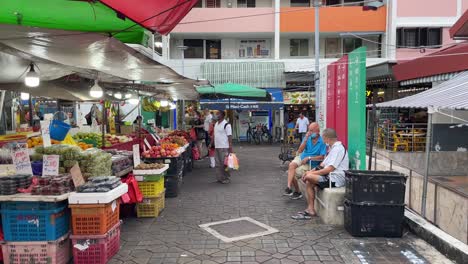 People-chit-chat-and-buy-fruits-at-the-neighbourhood-fruit-stall-in-Chong-Pang-City,-Yishun,-Singapore