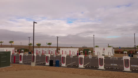Tesla-Supercharger-station-with-many-charging-stations-all-on-solar-power,-low-drone-flyover-4k