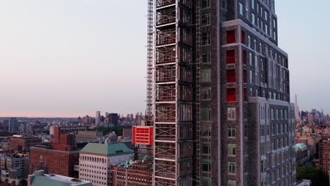 Aerial-view-around-the-construction-elevator-on-the-side-of-the-Claremont-Hall,-sunset-in-NYC,-USA---circling,-drone-shot