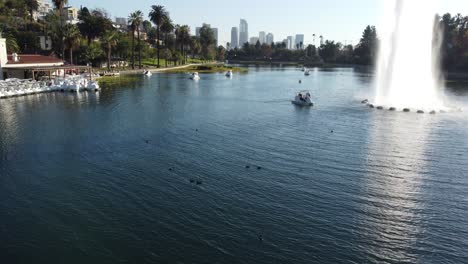Aerial-View-of-Echo-Park-and-People-on-Paddle-Boats-in-Lake-by-Fountain-With-Downtown-LA-in-Background
