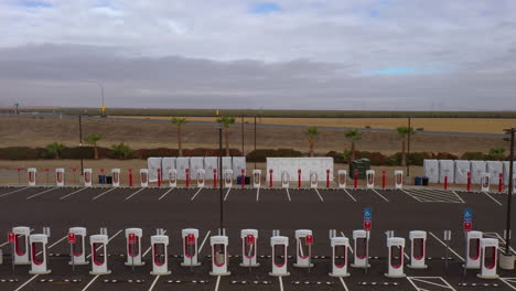 Largest-Tesla-Supercharger-Station-in-California-at-Harris-Ranch-in-Coalinga,-drone-pullback-shot