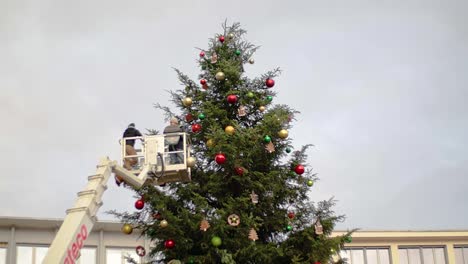 Crane-with-two-workers-rising-close-to-Christmas-tree-for-decoration-work