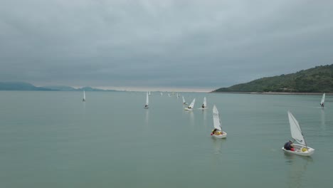Numerous-sailing-dinghies-carrying-out-sailing-lesson-in-the-bay-on-a-cloudy-day