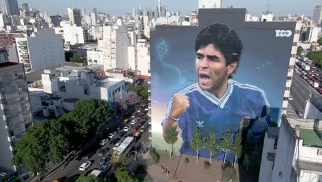 Giant-mural-decorates-the-cityscape-of-Buenos-Aires,-paying-tribute-to-late-soccer-legend-Diego-Maradona-on-his-second-anniversary-of-death-in-the-capital-city-of-Argentina,-aerial-dolly-in-shot