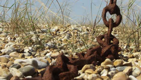 Rusty-chain-swinging-in-the-wind-on-the-pebble-beach