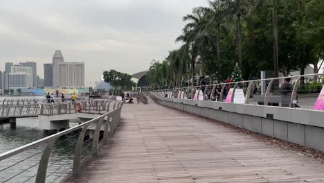 Day-view-of-tourists-and-locals-walking-at-the-waterfront,-Marina-Bay,-Singapore