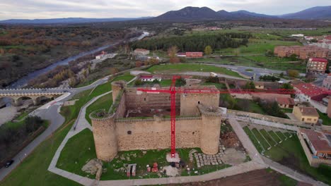 Drone-flying-over-a-castle-under-renovation-and-reconstruction-in-a-village-of-Avila,-Spain
