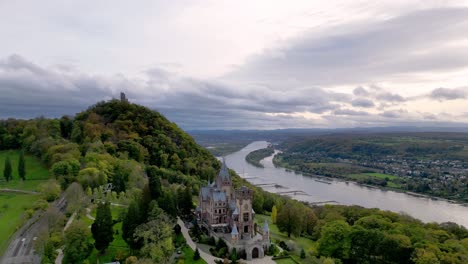Push-out-shot-of-he-Drachenburg-Castle-situated-in-the-Drachenfels,-Königswinter,-Germany-with-a-beautiful-autumn-sky-and-the-Rhein-river-in-the-background