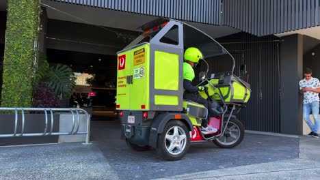Australia-post-postman-driving-battery-operated-electric-vehicle-on-the-road-delivering-parcels-to-door,-technology-transformation-and-environmental-friendly-with-reduction-of-carbon-emission