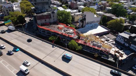 Aerial-view-of-a-construction-site-near-the-interstate-278,-in-sunny-Brooklyn,-NY---orbit,-drone-shot