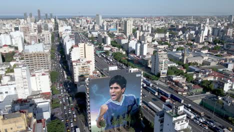 Vista-Aérea-De-Gran-Angular-Del-Barrio-Constitución-Con-Un-Mural-Gigante-De-Diego-Maradona-Pintado-En-La-Pared-Dedicado-A-La-Gloria-Del-Jugador-De-Fútbol-De-Las-últimas-Copas-Del-Mundo-En-Su-Aniversario-De-Muerte