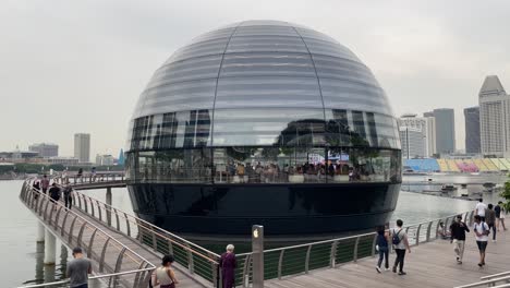 People-walks-and-visit-the-futuristic-waterfront-Apple-flagship-retail-store-in-Marina-Bay,-Singapore