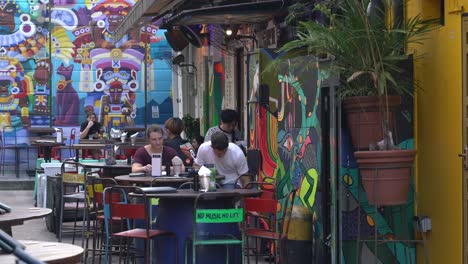 Tourists-chit-chat-and-check-the-menu-for-drinks-and-snacks-at-the-pub-in-Haji-Lane,-Singapore