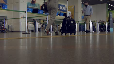 ground-level-shot-of-passengers-with-luggage-trolleys-passing-the-baggage-drop-off-in-the-airport