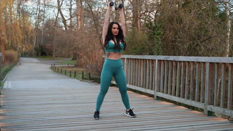 Sporty-women-lifting-weights-in-a-park-on-the-bridge