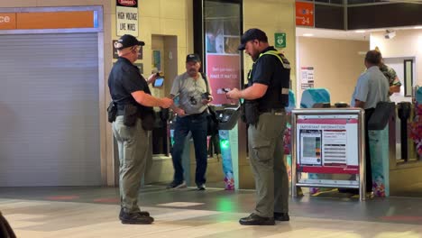 Authorised-uniform-ticket-inspectors-waiting-outside-of-the-gated-railway-station,-catching-fare-evasion-train-travellers,-ensuring-passengers-have-a-valid-ticket-at-Fortitude-Valley,-Brisbane