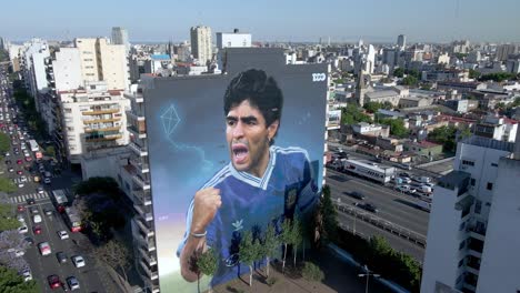 Street-art-mural-depicting-Argentine-soccer-legend-in-neighborhood-of-Constitucion,-featuring-Maradona-in-1990-World-Cup,-celebrating-his-glorious-victory-on-his-anniversary-of-death,-aerial-shot