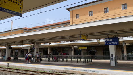 Passengers-arriving-at-train-station-platform-to-catch-departing-train-in-Pisa-Italy
