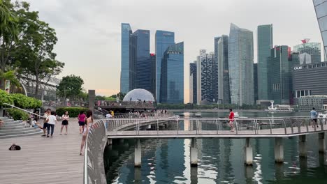 People-walks-outside-the-waterfront-retail-store-of-Louis-Vuitton-and-against-the-modern-skyline-of-Marina-Bay,-Singapore