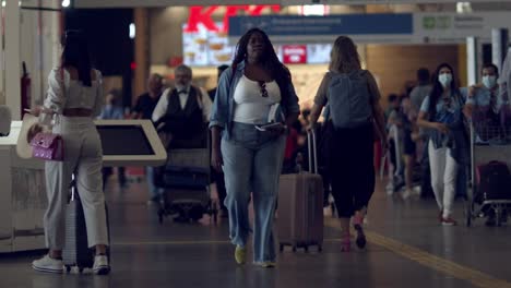 slow-motion-shot-of-travelers-walking-through-the-busy-departure-hall-in-the-airport-with-their-luggage