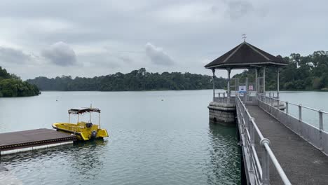 Tranquillity-of-the-calm-streamflow-against-the-view-of-a-small-yellow-boat-and-Pavillion-in-MacRitchie-reservoir,-Singapore