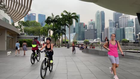 La-Gente-Anda-En-Bicicleta,-Trota,-Camina-Tranquilamente-Y-Descansa-Frente-A-La-Increíble-Vista-De-Marina-Bay-Fuera-De-Marina-Bay-Sands-En-Singapur