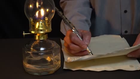 Person-writing-with-a-quill-pen-and-oil-lamp