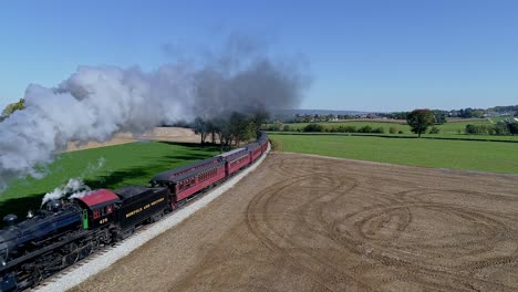 Drone-Above-and-to-the-Side-View-of-a-Steam-Passenger-Train-Rounding-a-Curve-on-a-Sunny-Day