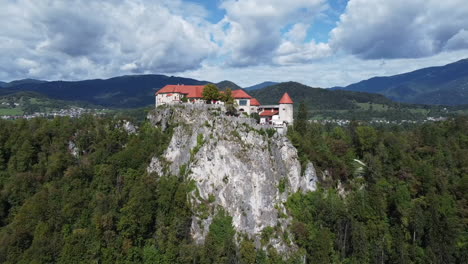 Tiro-De-Dron-Del-Lago-Bled-En-Eslovenia---Dron-Está-Dando-Vueltas-Alrededor-Del-Castillo-Local,-Revelando-Las-Montañas